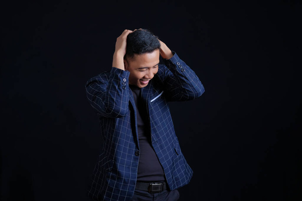 Frustrated young businessman wearing blue suit isolated on black background - Fotó, kép