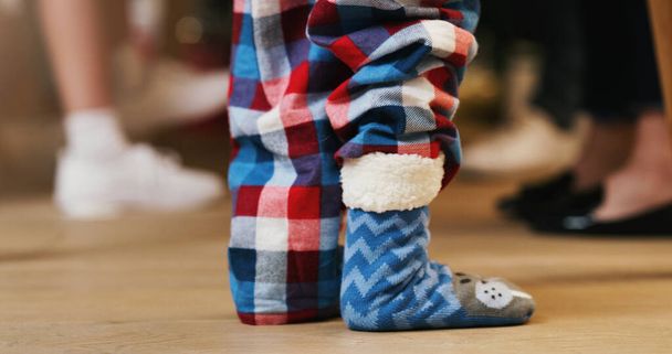 Τίποτα δεν λέει τα Χριστούγεννα όπως οι ζεστές κάλτσες για τα παιδιά. ένα αγνώριστο αγοράκι που φοράει χαριτωμένες χνουδωτές κάλτσες κατά τη διάρκεια ενός Χριστουγεννιάτικου πάρτι με την οικογένειά του στο σπίτι - Φωτογραφία, εικόνα
