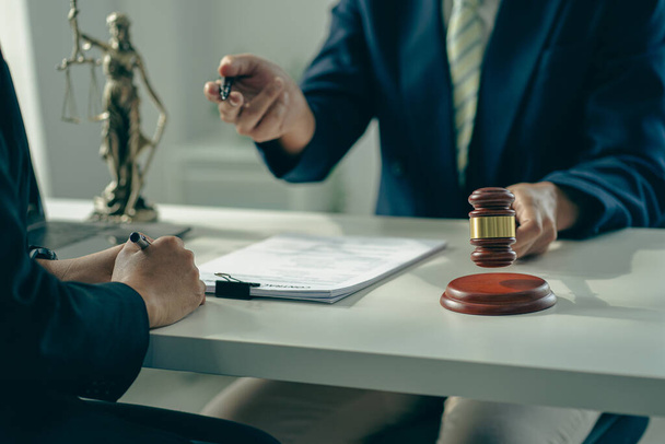 Businessmen and lawyers discuss contract documents with brass scales and judges' hammers on wooden tables in the office. Legal services. Advice. Justice concept. - Photo, image