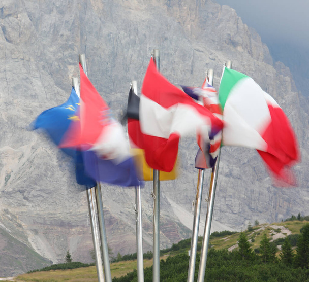 many international flags of nations waving intentional blur and mountains in the background - Foto, afbeelding