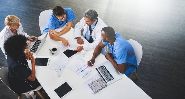 Team of medical workers sitting and meeting with laptops around table. Doctors and staff discussing papers and test results. Healthcare experts handling daily tasks and duties. - Photo, image