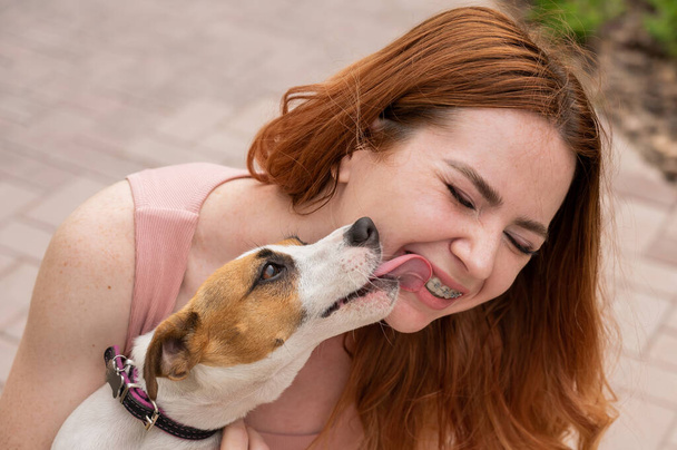 Dog jack russell terrier licks the owner in the face outdoors - Foto, immagini