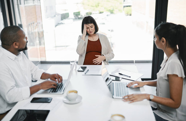 Can we take a break please. a pregnant young businesswoman feeling stressed during a team meeting in a modern office - Foto, immagini
