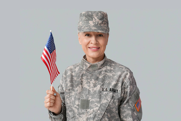 Mature female soldier with USA flag on grey background - Foto, Imagem