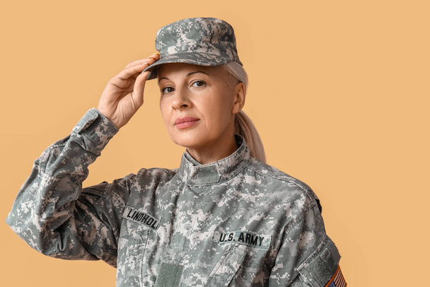 Mature female soldier on beige background - 写真・画像
