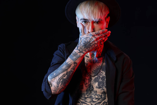 Young tattooed man on black background - Fotoğraf, Görsel