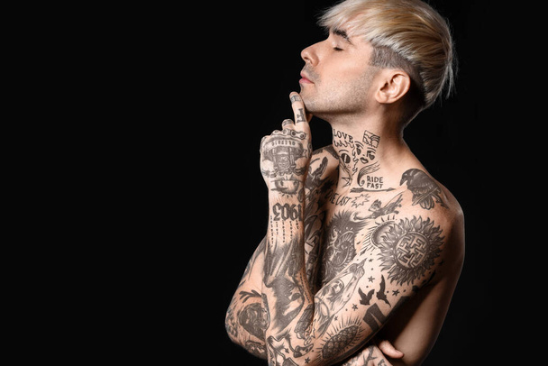 Young tattooed man on dark background - Foto, afbeelding