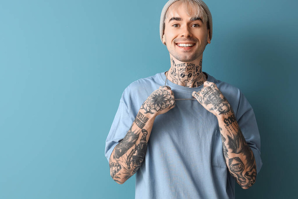 Young tattooed man on blue background - Foto, Imagen