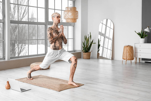 Young tattooed man practicing yoga at home - Zdjęcie, obraz
