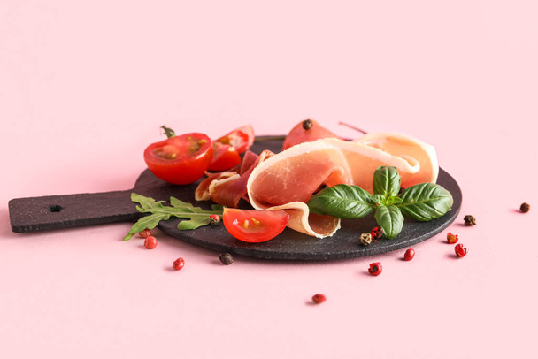 Slate board with delicious jamon, spices and tomatoes on pink background - Fotografie, Obrázek