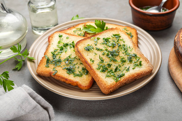 Plate of toasts with garlic and parsley on table - Fotó, kép