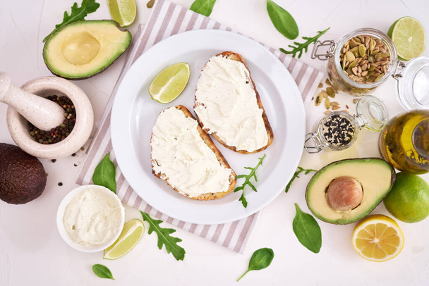 Avocado and cream cheese toasts preparation - grilled or toasted bread with cheese smeared . - Foto, Imagen