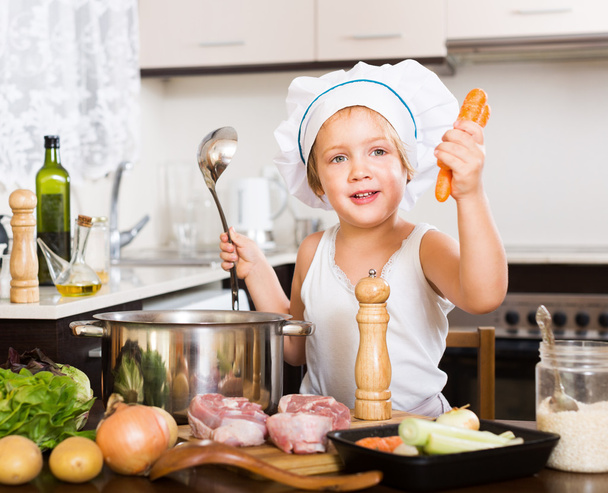 Happy child cooking soup with vegetables - Fotó, kép