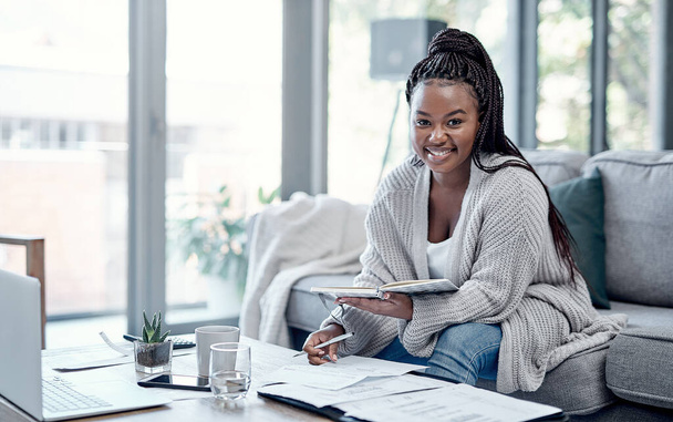 Afford the life of your dreams with good financial planning. Portrait of a young woman going over paperwork and using a laptop on the sofa at home - Foto, Imagen