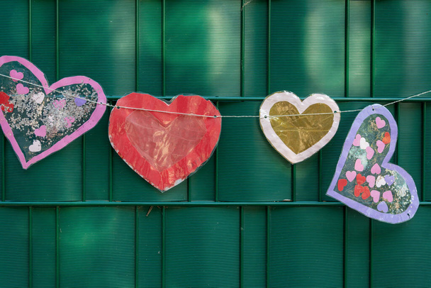 handmade hearts made of cardboard in front of a fence - Фото, изображение
