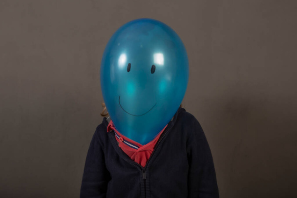 Painted blue balloon head with a happy face on a child's body - Fotoğraf, Görsel