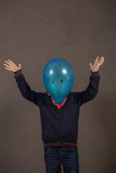 Painted blue balloon head with a happy face on a child's body - Фото, зображення
