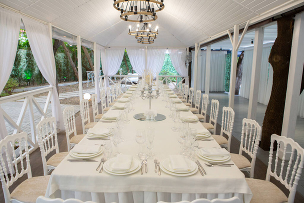 Empty banquet hall ready to receive guests on the summer terrace. white festive table - Fotografie, Obrázek