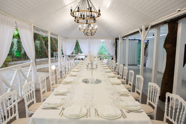 Порожній банкетний зал готовий приймати гостей на літній терасі. білий святковий стіл
 - Фото, зображення
