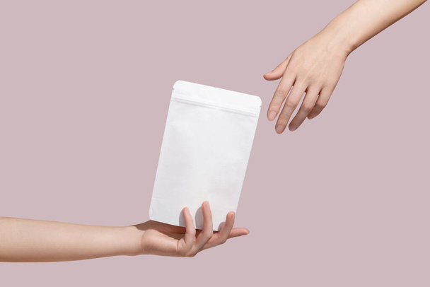 Female hand holds white cardboard packaging for tea/coffee/snack on pink background. Branding and packaging mockup. High quality photo - Fotoğraf, Görsel