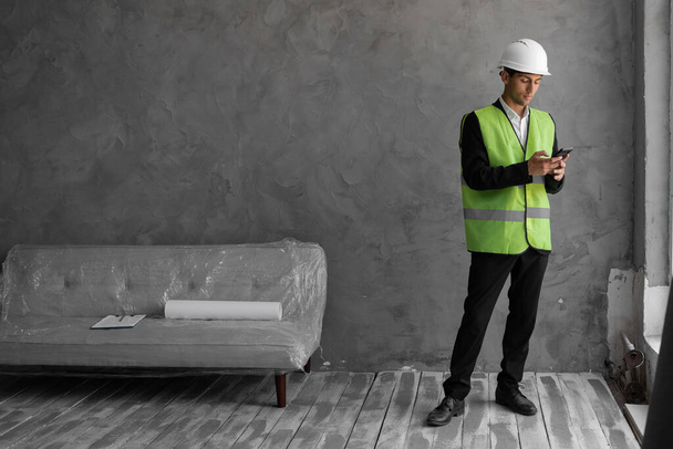 Muslim professional builder engineer with safety helmet using phone, home renovation and communication concept - 写真・画像