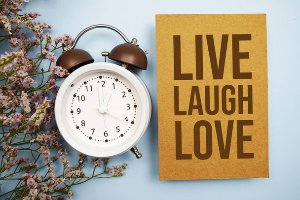 Live Laugh Love written on paper card with flower and alarm clock on blue background - Zdjęcie, obraz
