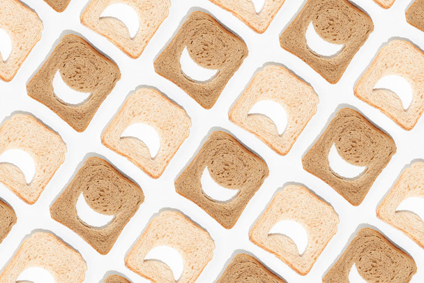 Creative emoji pattern made of slices of white and whole-grain brown toast bread on isolated pastel white background. Minimal flat lay texture. The concept of health benefits or food comparison. - Foto, imagen