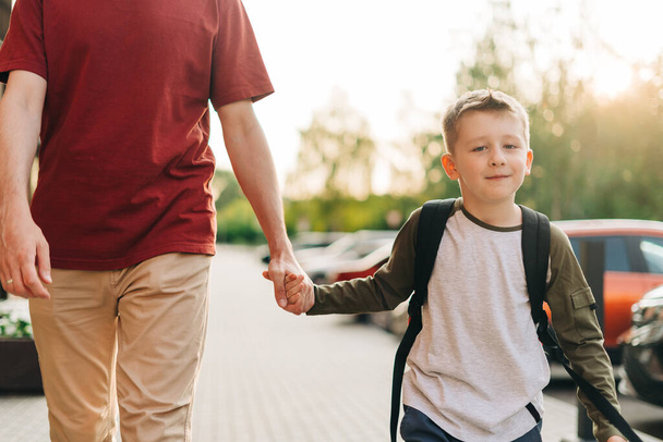 Happy father and kid son going to classes. Parent take child boy to school in first grade. Pupil of primary school go study with backpack outdoors in city street. Beginning of lessons. Back to school. - Zdjęcie, obraz