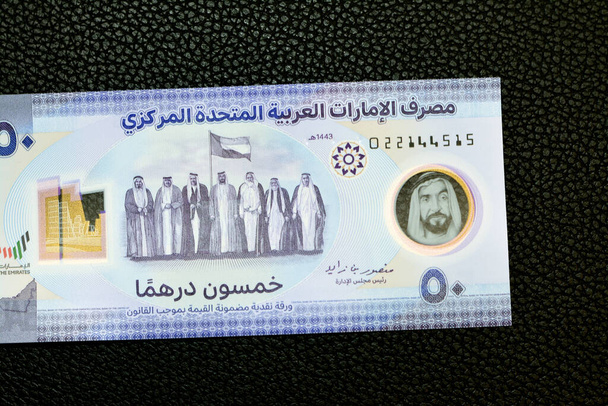 obverse side of the new polymer commemorative 50 fifty Dirhams with Memorial to the martyrs of the Emirates UAE, seven founding fathers with flag after signing the union document isolated on black - Fotó, kép