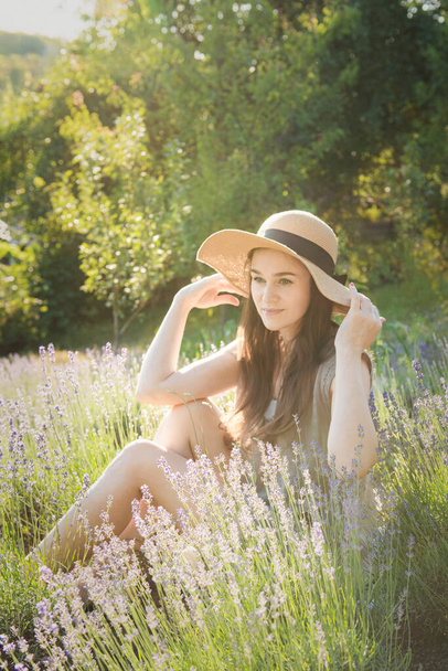 Beautiful young woman on lavender field. Sunset. Attractive young female outdoors. - Photo, Image