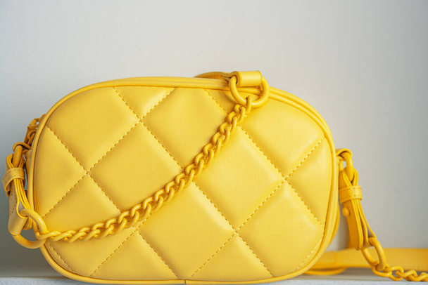 Yellow cross body quilted bag. Ladies bright-colored handbag on gray background. Yellow woman bag. - Photo, Image