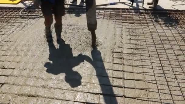 Construction worker is directing the pump tube on right direction, pouring layer of concrete in building foundation covering square reinforcement. - Záběry, video