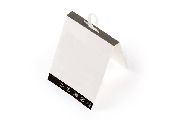 Blank white carton hanging tag with clothing care symbols on a plastic hanger on a white background - Fotografie, Obrázek