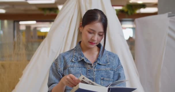 A beautiful Asian woman is happy to read a book. 4K DCI (The submitted footage is a grouping shooting arrangement) - Imágenes, Vídeo