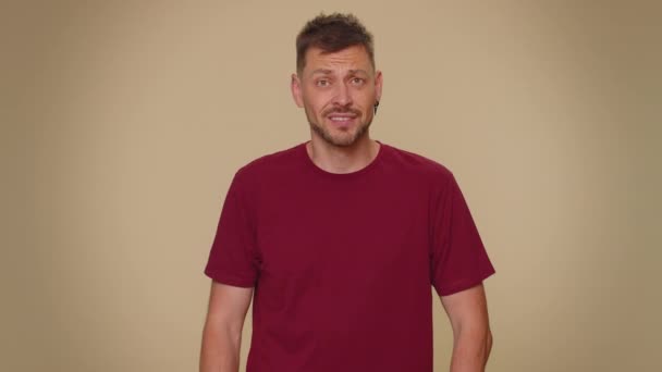 You are crazy, out of mind. Bearded handsome young man pointing at camera and showing stupid gesture, blaming some idiot for insane plan. Adult stylish guy isolated on beige studio background indoors - Záběry, video