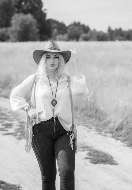 Woman Plus size in American country style black boho jacket, with a fringe, shirt and cowboy hat at nature - Fotoğraf, Görsel