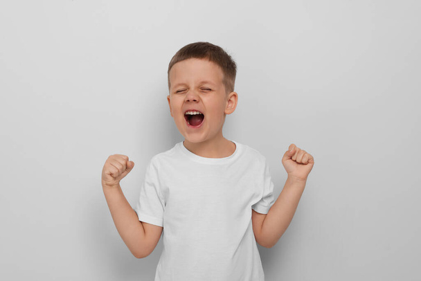 Angry little boy screaming on white background. Aggressive behavior - Photo, image