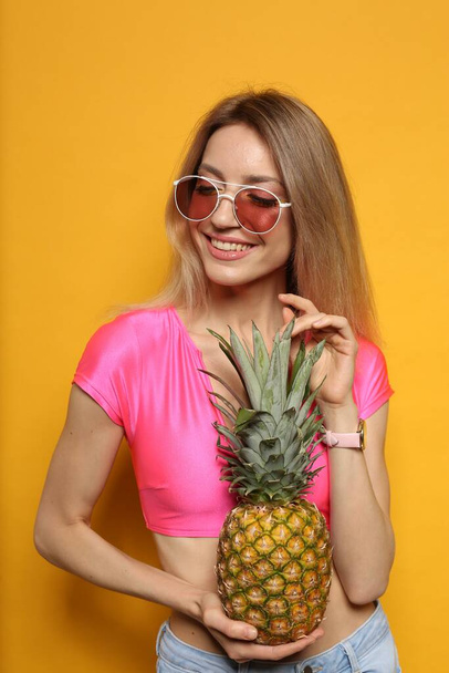 Young woman with fresh pineapple on yellow background. Exotic fruit - Foto, Imagem