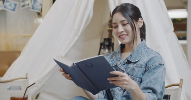 Красивая азиатка с радостью читает книгу. 4K DCI (Представленные кадры - это грубая съемка)) - Кадры, видео