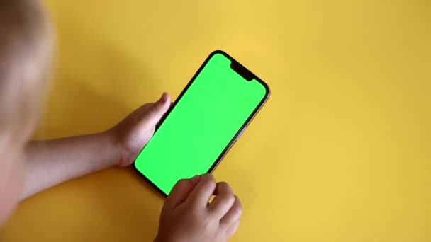 Preschool Girl Use Smartphone With a Green Screen Layout. Chroma key mock-up on smartphone in hand. Color Key. Watching content, Videos, photos, playing a game. Slow motion. - Filmagem, Vídeo