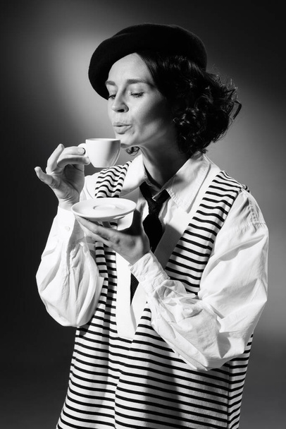Portrait of tender woman in stylish classical clothes drinking tea or coffee. Black and white photography. Retro style image. Monochrome effect. Concept of fashion, style, history, beauty, arts - Foto, Imagem