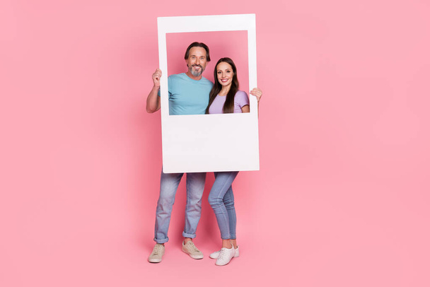 Full size portrait of two lovely nice partners hold paper album card isolated on pink color background. - Foto, Bild