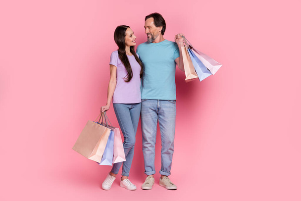 Full body portrait of two positive friendly people embrace look each other hold packages isolated on pink color background. - Fotografie, Obrázek