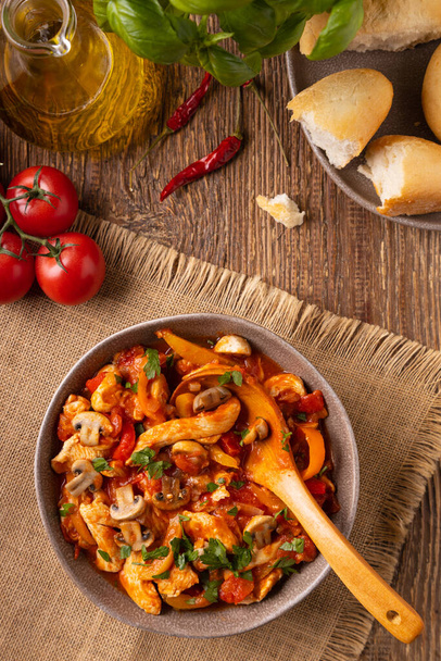 Chicken stew with peppers, mushrooms and tomatoes. Wooden background.  - Foto, immagini