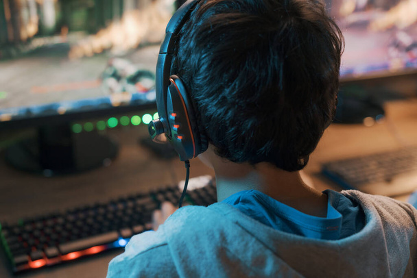 Teenager wearing a headset and playing online video games at home, 3D shooter games - Photo, image