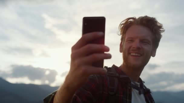 Closeup excited blogger take selfie on mobile phone outdoors. Hipster celebrate reach peak on mountains. Emotional traveling guy express happiness on digital smartphone. Technology leisure concept. - Video