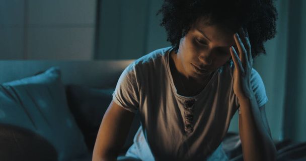 Depressed african american woman sitting on bed, she is suffering from insomnia - Foto, Bild