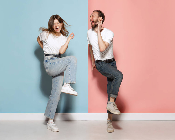 On style. Young stylish happy man and excited girl dancing hip-hop at studio on blue and pink trendy color background. Human emotions, youth, love and lifestyle concept - 写真・画像