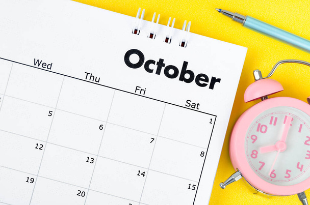 October 2022 desk calendar and pen with plant pot on yellow background. - Photo, Image