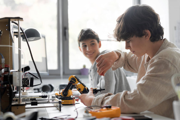 Young students using a 3D printer in the lab at school, one is using a screwdriver - Foto, Imagem